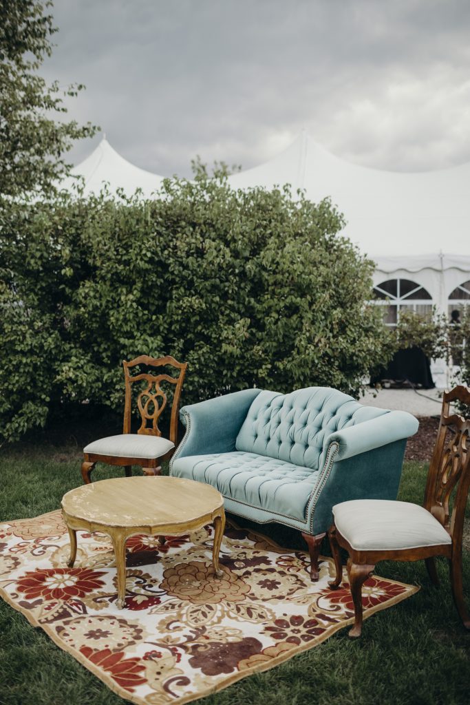 Classy earthy wedding rentals with couch and vintage chairs and rug