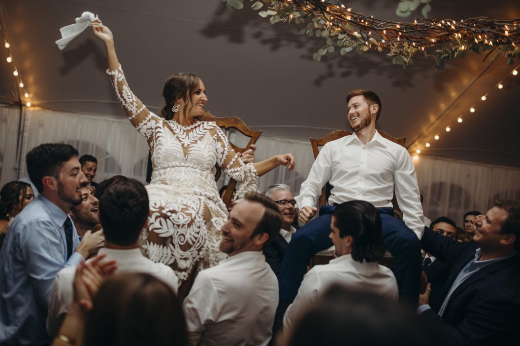 Wedding traditional Hora dance, bride and groom lifted up on chairs