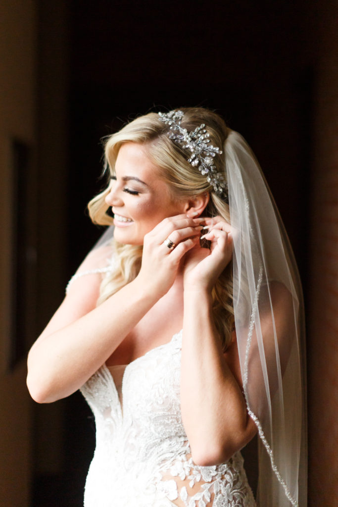 Beautiful bride puts on her bridal jewelry. Shows off her bridal headpiece.