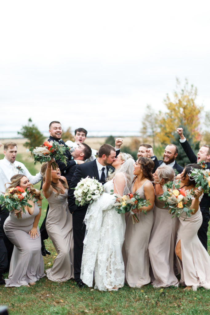 Bridal party goals with groomsmen in black suits and bridesmaids in gray lavender dresses.