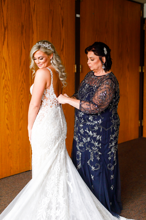 Mom zipping up bride while bride gets ready.